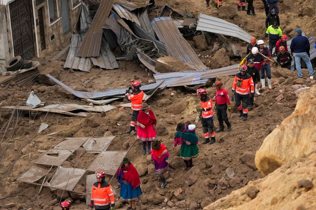 Rescue workers and residents walk amid the debris (Dolores Ochoa/AP)