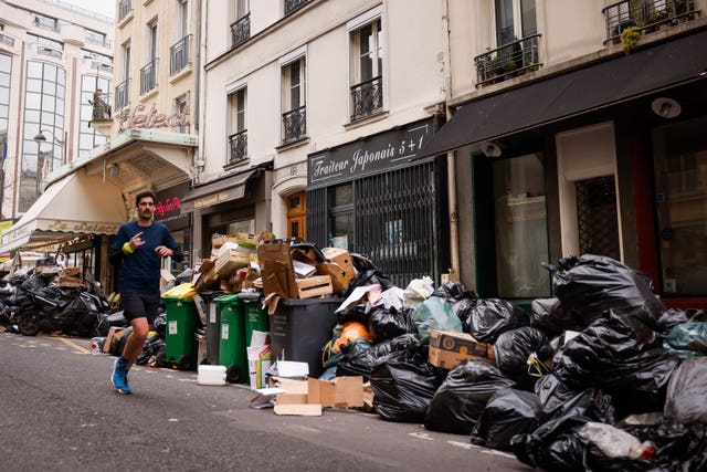 A man jogs past uncollected rubbish bags in Paris 