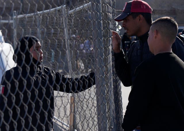 Migrants ask a member of the Mexican National Guard if there is any new information available regarding the victims of the fire 