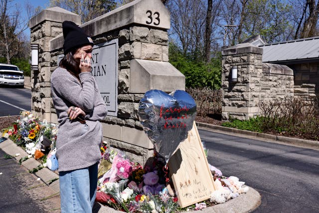 A woman wipes away tears as she visits a memorial at the entrance to The Covenant School on Wednesday in Nashville