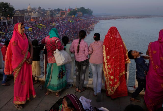 Families watch from a bridge as thousands of people enter the holy River Saryu in Ayodhya, India