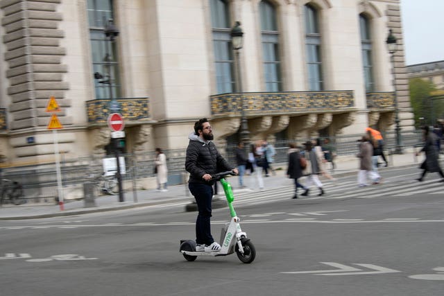 A man rides a scooter in Paris, Friday, march 31, 2023