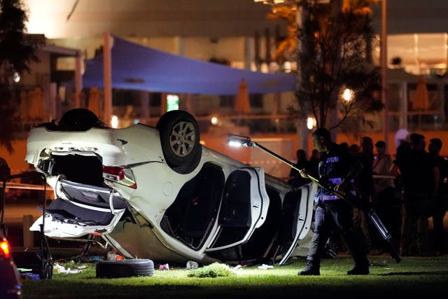 Israeli police and emergency services work around a car involved in an attack in Tel Aviv, Israel, Friday, April 7, 2023