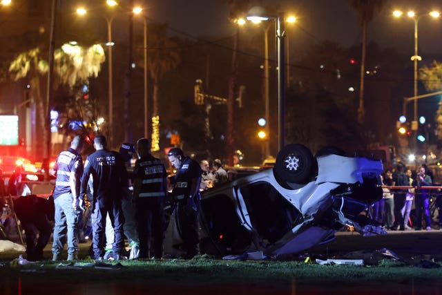 Israeli police and emergency service stand around a car involved in an attack in Tel Aviv, Israel, Friday, April 7, 2023