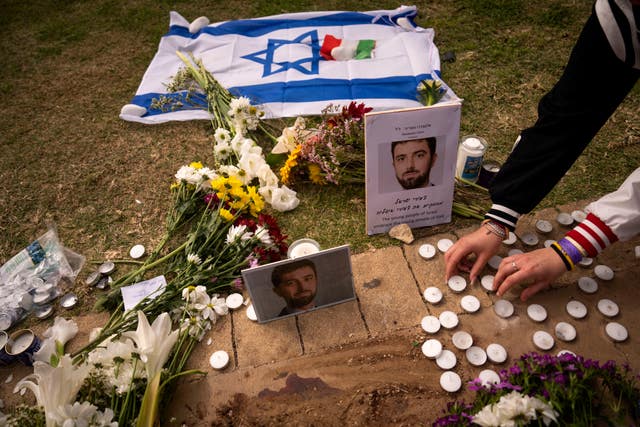 People lay flowers and candles next to photos showing Alessandro Parini, an Italian tourist who was killed in a Palestinian attack, in Tel Aviv on Saturday 