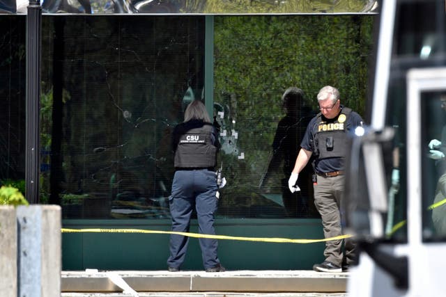 A Louisville Metro Police crime scene technician photographs bullet holes in the glass of the Old National Bank building in Louisville