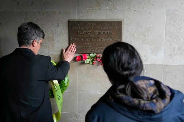 A man lays flowers during a memorial service marking the 24th anniversary of the killing of prominent editor and newspaper publisher Slavko Curuvija, who was fiercely critical of the government, in Belgrade, Serbia