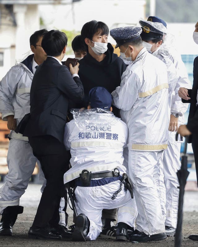 A man, centre, is detained after what appeared to be a smoke bomb was thrown at a port in Wakayama