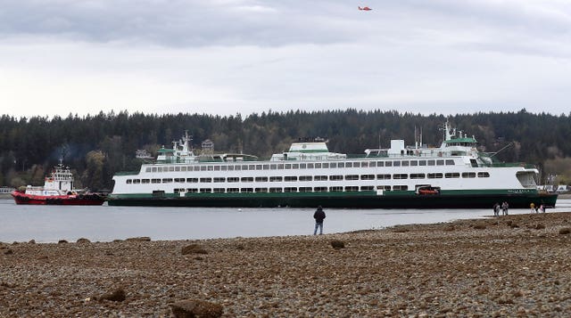 People stand on the shore while looking at the Walla Walla passenger ferry after it ran aground near Bainbridge Island west of Seattle