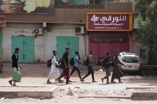 People walk past shuttered shops in Khartoum, Sudan 