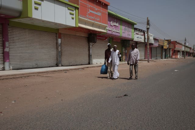 People walk past shuttered shops in Khartoum, Sudan 