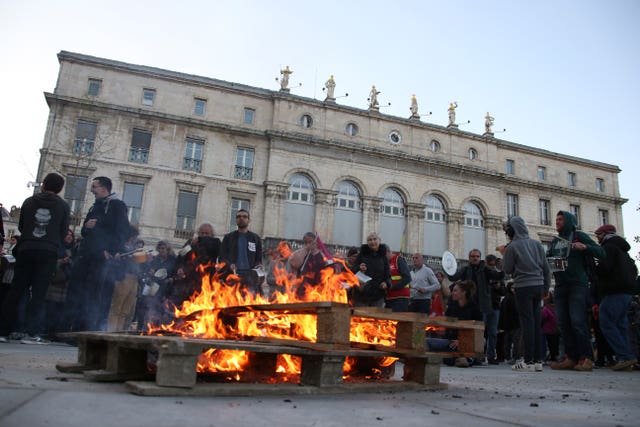 People bang pots and pans behind burning palettes in Bayonne, south-western France, while French President Emmanuel Macron seeks to defuse tensions in a televised address to the nation 