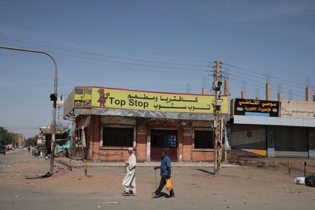 People walk past closed shops in Khartoum, Sudan