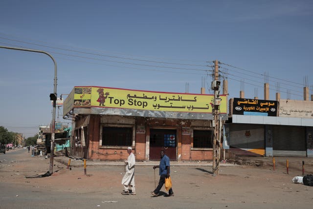 People walk past shuttered shops in Khartoum, Sudan 