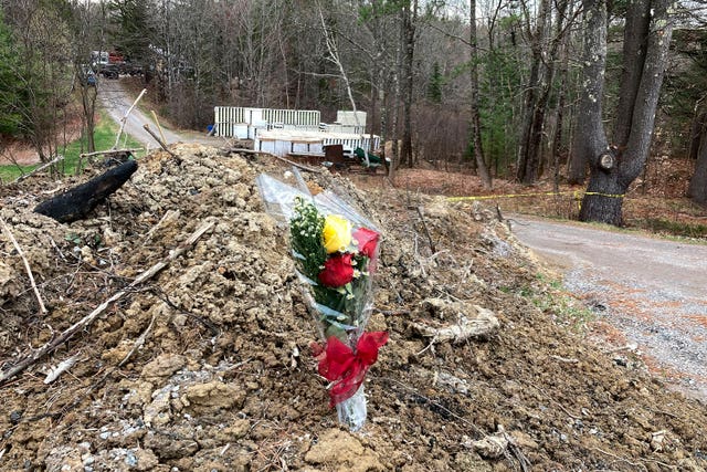 A lone bouquet of flowers marks a desolate makeshift memorial at the end of a driveway at a Bowdoin, Maine