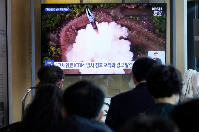A TV screen shows an image of a North Korean missile launch 