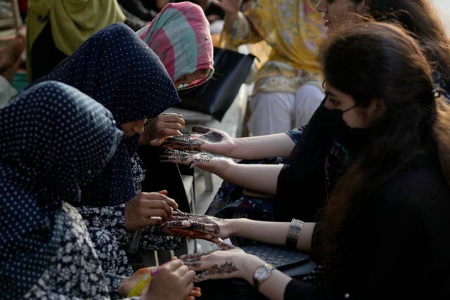 Beauticians paint the hands of customers with traditional henna in preparation for the upcoming Eid al-Fitr celebrations, in Karachi, Pakistan