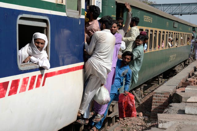 People ride on an overcrowded passenger train, to reach their villages and cities to celebrate Eid, in Lahore, Pakistan