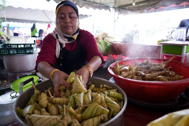 A Malaysian Muslim vendor cooks ketupat - rice cakes wrapped in woven palm leaf pouches - ahead of Eid celebrations in Kuala Lumpur