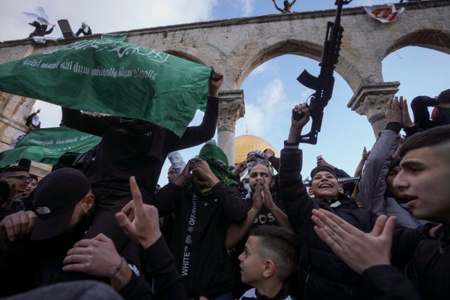 Palestinians brandish a toy gun and wave the flag of the Hamas militant group in protest against Israel during Eid celebrations by the Dome of the Rock shrine in the Al Aqsa Mosque compound in Jerusalem’s Old City