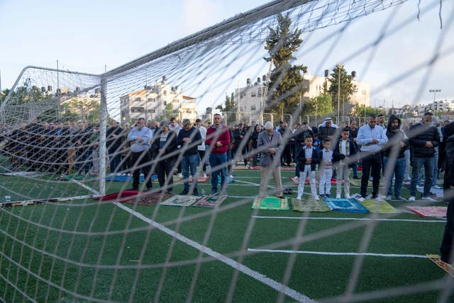 Palestinian Muslims perform Eid prayers at a football pitch in the West Bank city of Beitunia