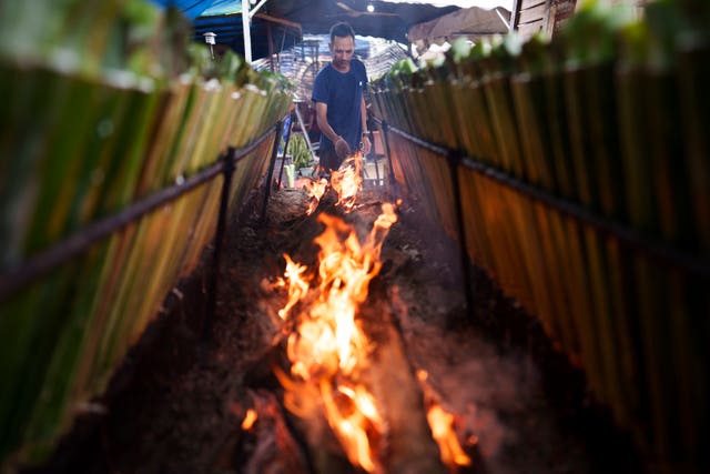 A Malaysian Muslim vendor cooks lemang - a traditional food of glutinous rice stuffed in bamboo sticks and cooked over charcoal fire - ahead of the Eid celebrations in Kuala Lumpur