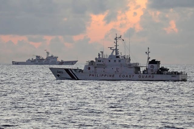 Philippine coastguard patrol vessel BRP Malapascua, right, passes by Chinese coastguard ship with bow number 5201 during sunrise near the Second Thomas Shoal