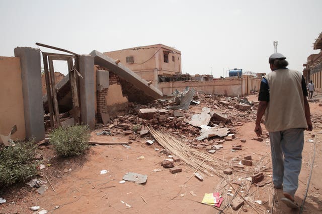 A man walks by a house hit in recent fighting in Khartoum