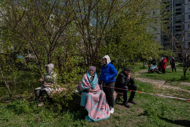 Residents sit outside a residential building hit during a Russian attack in Uman