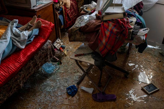 The body of a woman who died after a Russian attack on a residential area lies on a bed surrounded by debris in Uman