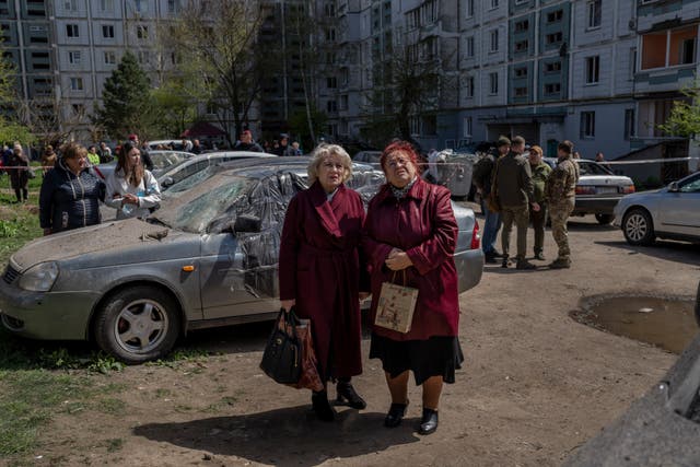 Residents watch the destruction of a residential building hit during a Russian attack in Uman