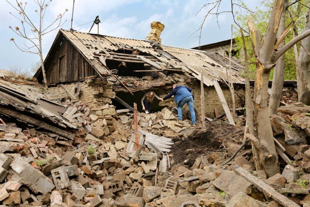 People help each other leave a damaged house after shelling that, according to Russian officials in Donetsk, was conducted by Ukrainian forces in the capital of Russian-controlled Donetsk region