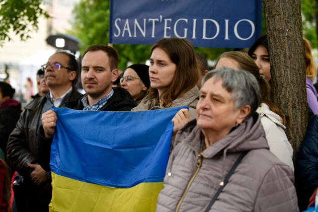 A couple hold a Ukrainian flag as they wait to see Pope Francis