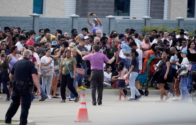 People gather across the street from a shopping center after shooting on Saturday, May 6, 2023, in Allen, Texas