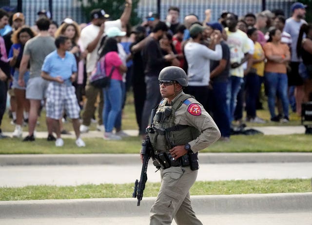 A law enforcement officer walks as people are evacuated from a shopping centre where a shooting occurred Saturday, May 6, 2023, in Allen, Texas