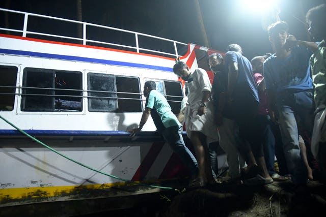 Rescuers and others pull ashore a tourist boat that capsized in Malappuram, Kerala, India