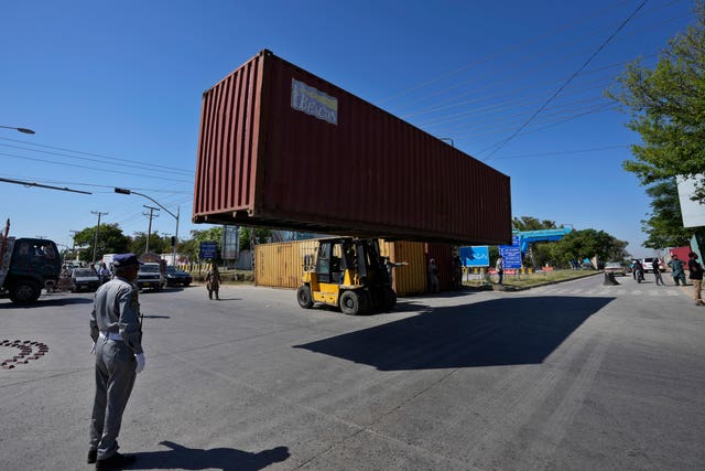 A shipping container is prepared to block a road leading to police headquarters