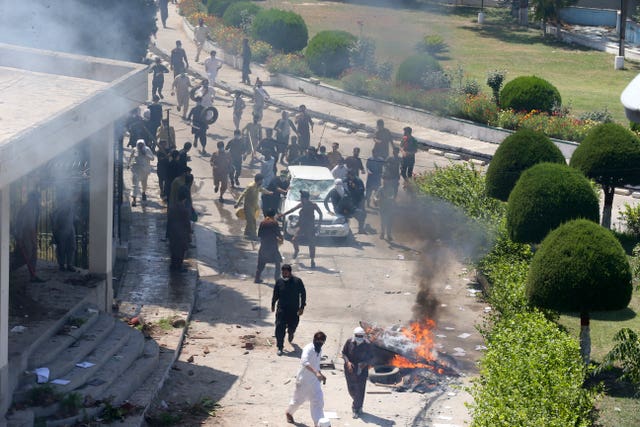 Supporters of Mr Khan damage a car inside the compound of Radio Pakistan in Peshawar 