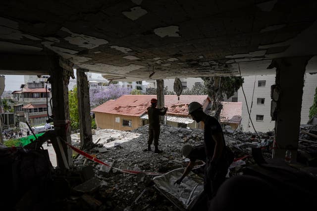 Israeli soldiers and municipality workers inspect the damage to an apartment building a day after it was hit by a rocket fired from the Gaza Strip, in Rehovot, Israel