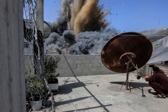 A Palestinian youth takes photos of an explosion from an Israeli air strike targeting a nearby building, which Israel says belonged to a Palestinian Islamic Jihad militant in Beit Lahiya, northern Gaza