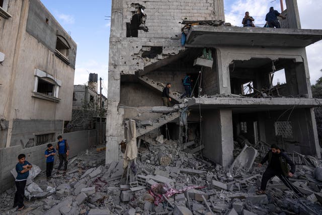 Palestinians inspect the site of an airstrike that the Israeli military said targeted the house of an Islamic Jihad member in Deir al-Balah in the central Gaza Strip 