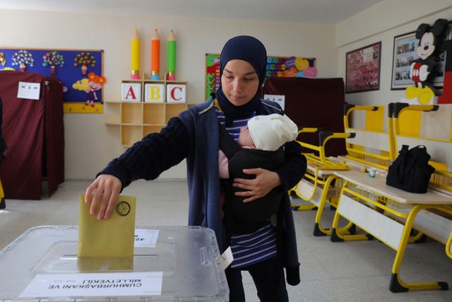 A woman with a baby votes at a polling station in Ankara 