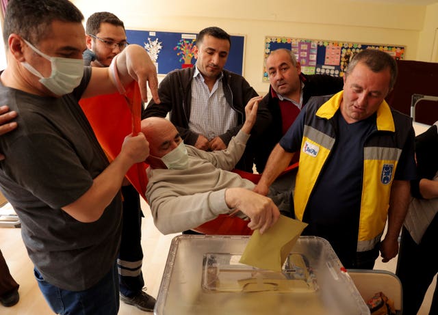 Cevat Cinar is carried on a stretcher to cast his ballot at a polling station in Ankara 