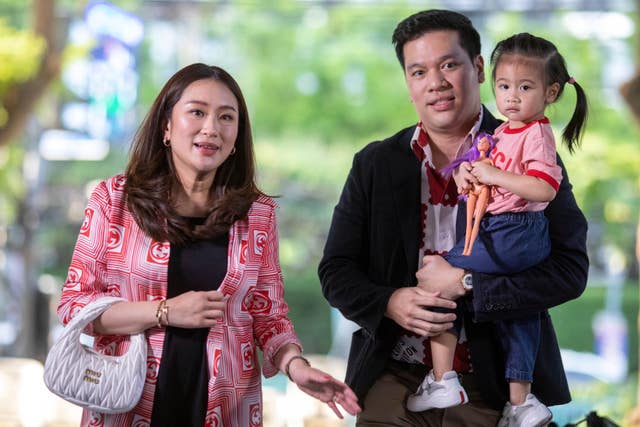 Paetongtarn Shinawatra, left, one of the prime minister candidates from Pheu Thai Party, arrives with her husband at party headquarters 