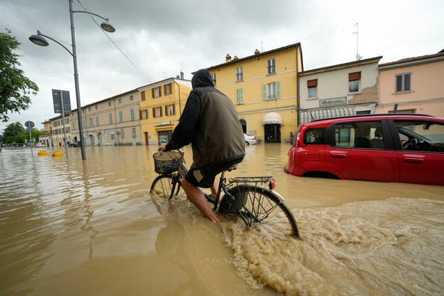 A cyclist rides through a flooded street in the village of Castel Bolognese