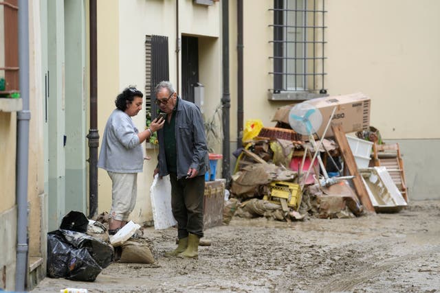 People stand in a road covered by mud in Faenza, Italy