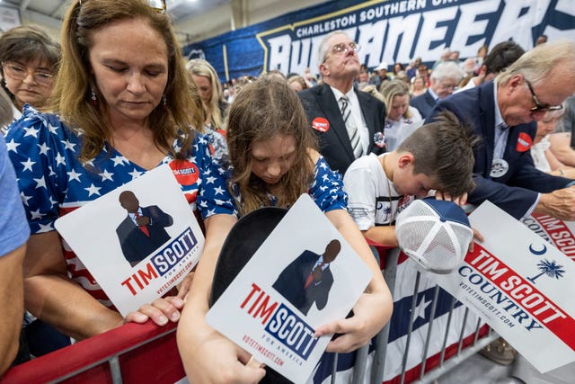 Traci Smith, far left, and her daughter Brooke, 12, bow their heads in prayer before Republican presidential candidate Tim Scott delivers his speech announcing his candidacy for president of the United States on the campus of Charleston Southern University in North Charleston, South Carolina