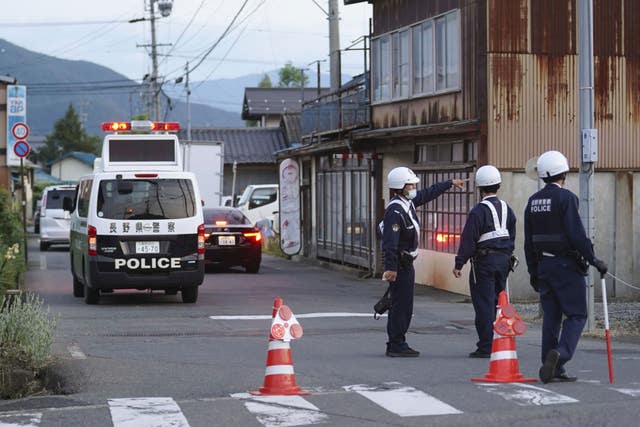 Police officers stand guard on a street leading to a building where a man was holed up in Nakano, central Japan