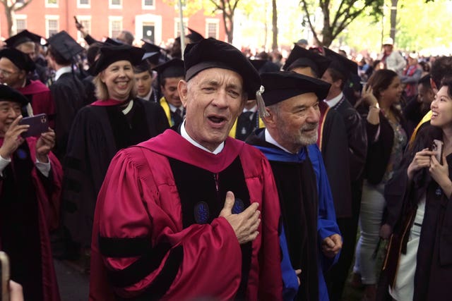 Actor Tom Hanks greets people as he walks in a procession though Harvard Yard