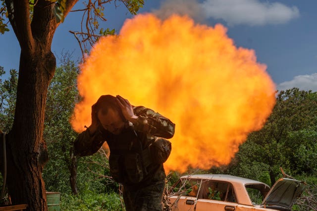 A Ukrainian soldier covers his ears while firing a mortar at Russian positions on the frontline near Bakhmut, Donetsk region